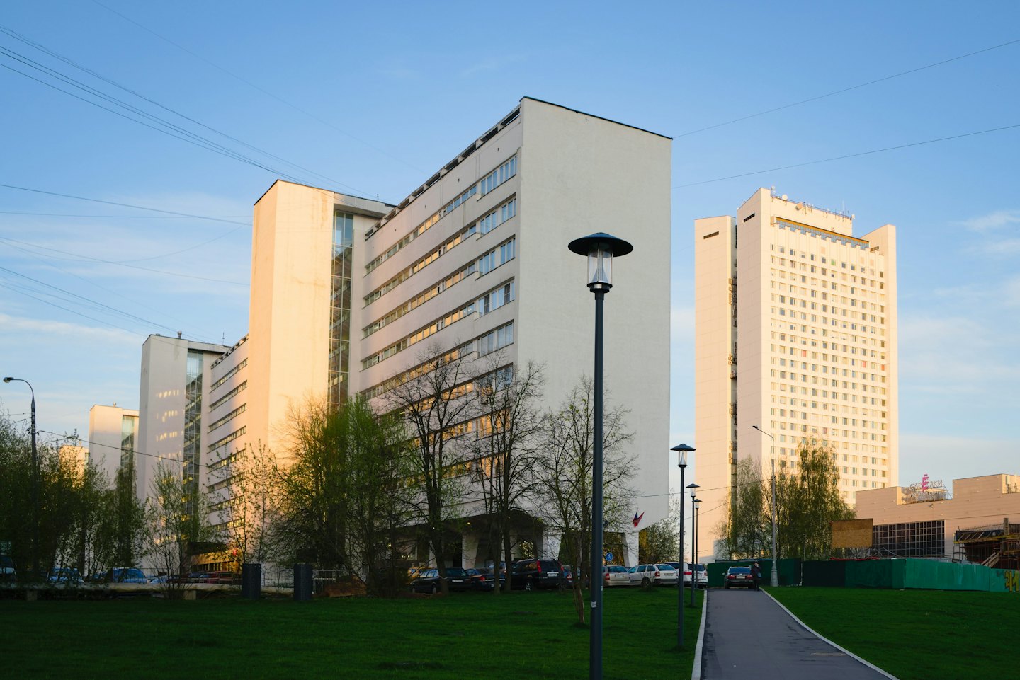 Nowoczesne wieżowce stoją za zagospodarowanym trawnikiem i ścieżką.